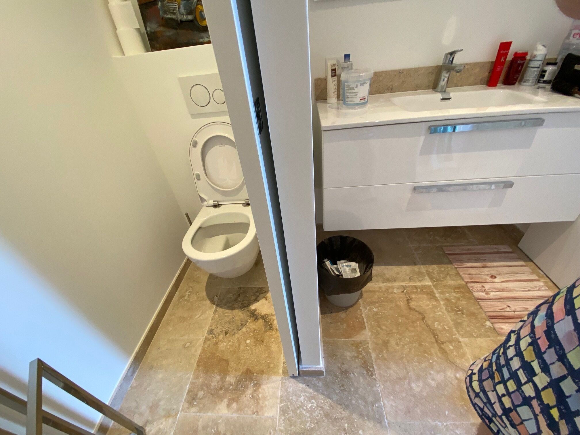 Et badeværelse med toilet, håndvask og skraldespand.