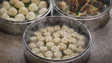 Three metal steamer baskets with food, one containing dumplings, another with a different type of dumpling, and the third with what appears to be meat and vegetables.