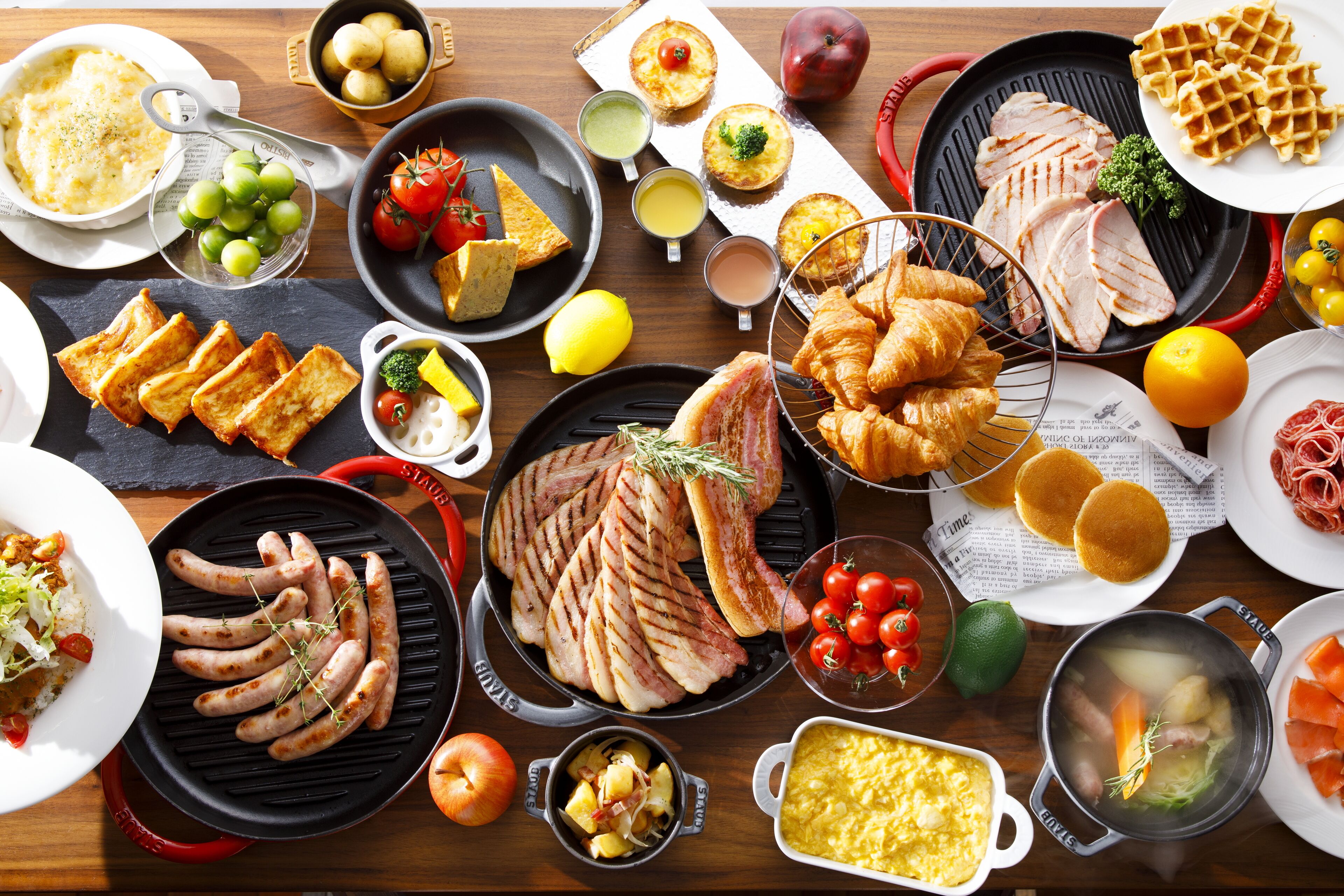 Diversos alimentos, como carnes a la parrilla, salchichas y pasteles, sobre una mesa de madera.