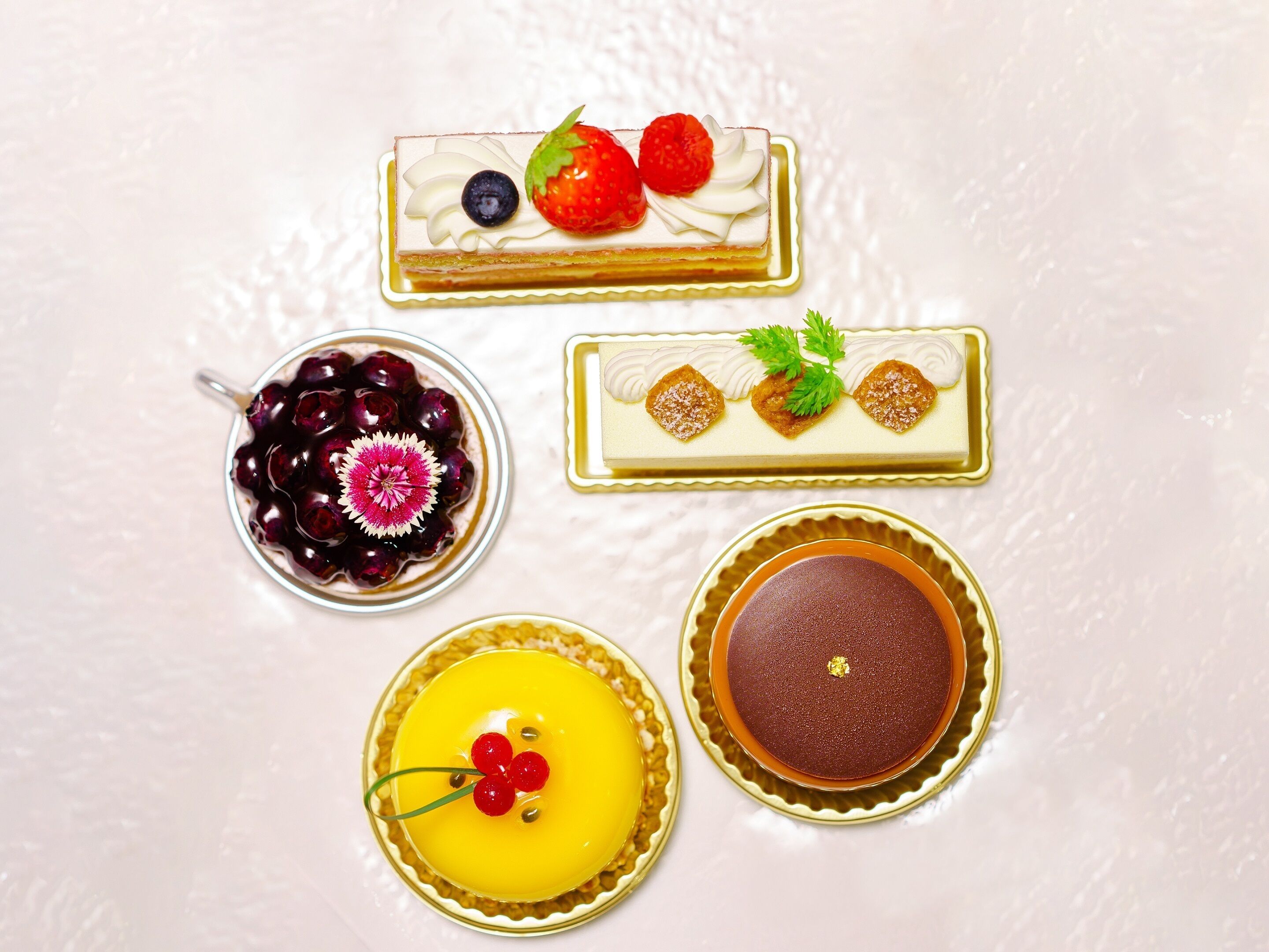 A variety of desserts including a chocolate cake, a fruit tart, a cherry dessert, and a cake with cream and berries.