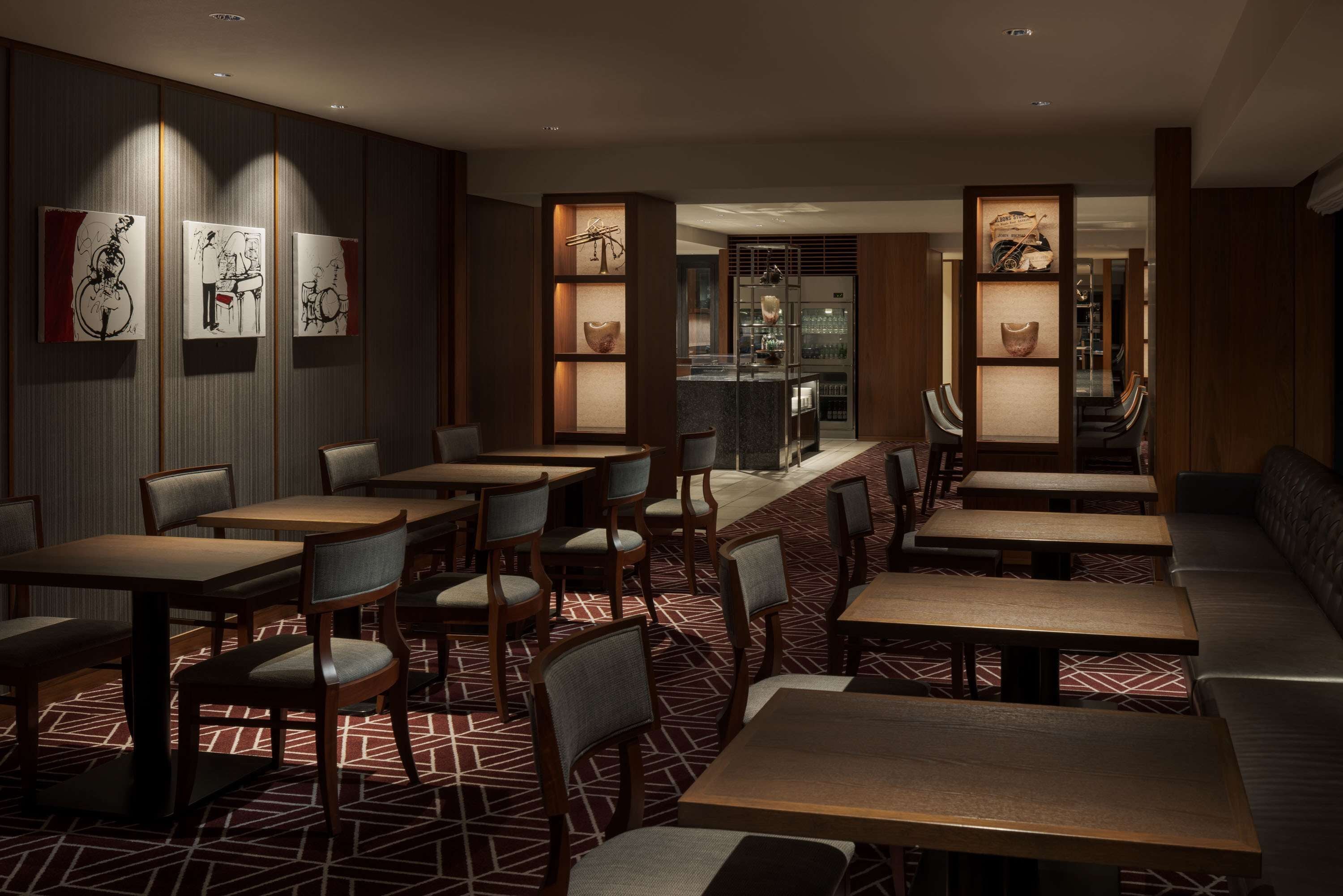 Un restaurant avec des tables et des chaises en bois, un sol à motifs et des œuvres d’art accrochées aux murs.