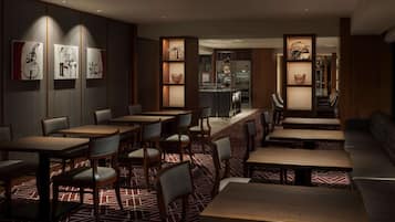 Un restaurant avec des tables et des chaises en bois, un sol à motifs et des œuvres d’art accrochées aux murs.