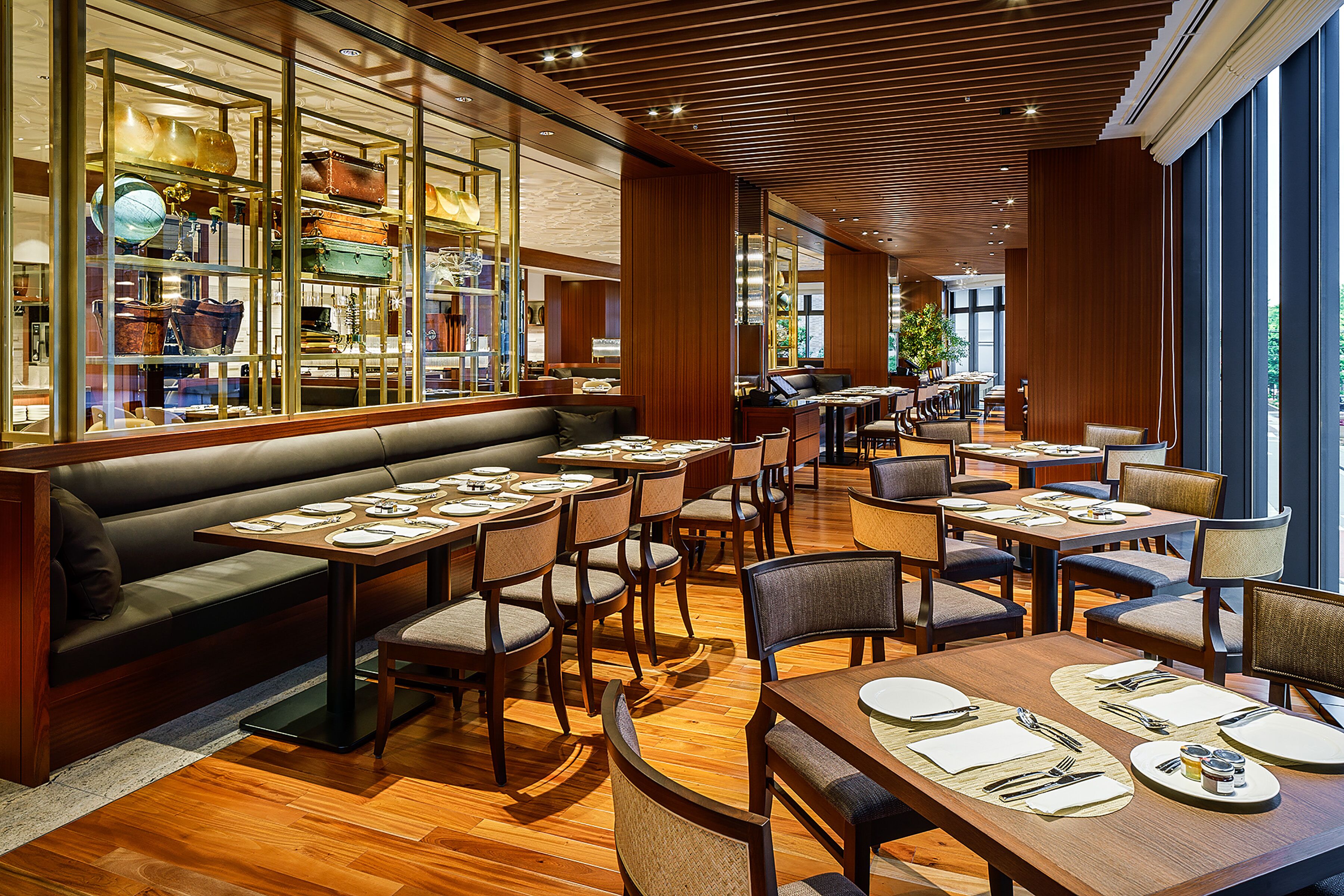 Un restaurant doté d’un plancher en bois, de tables recouvertes de nappes blanches et d’une variété de chaises.