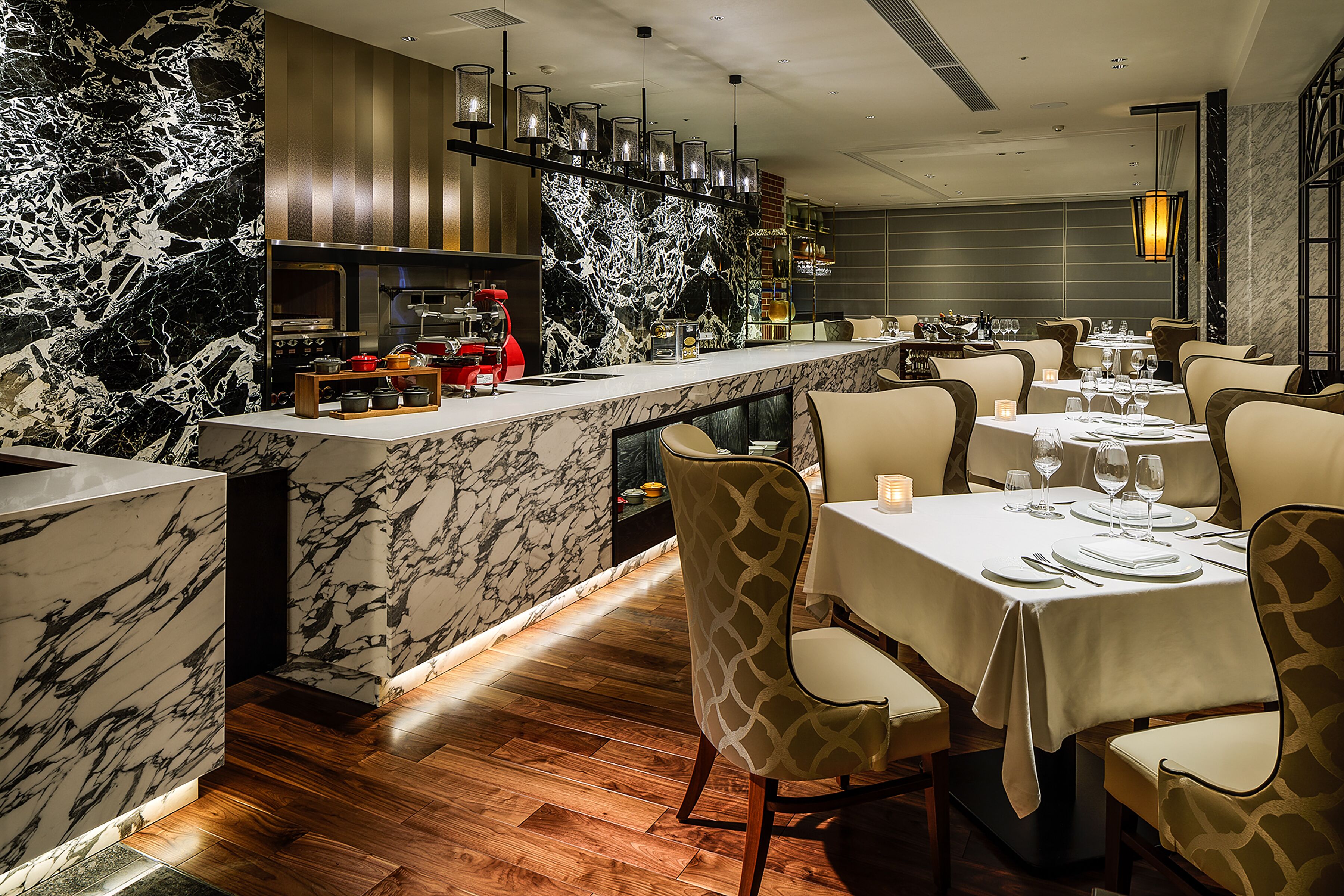 A modern restaurant with marble walls, wooden flooring, and a bar area.