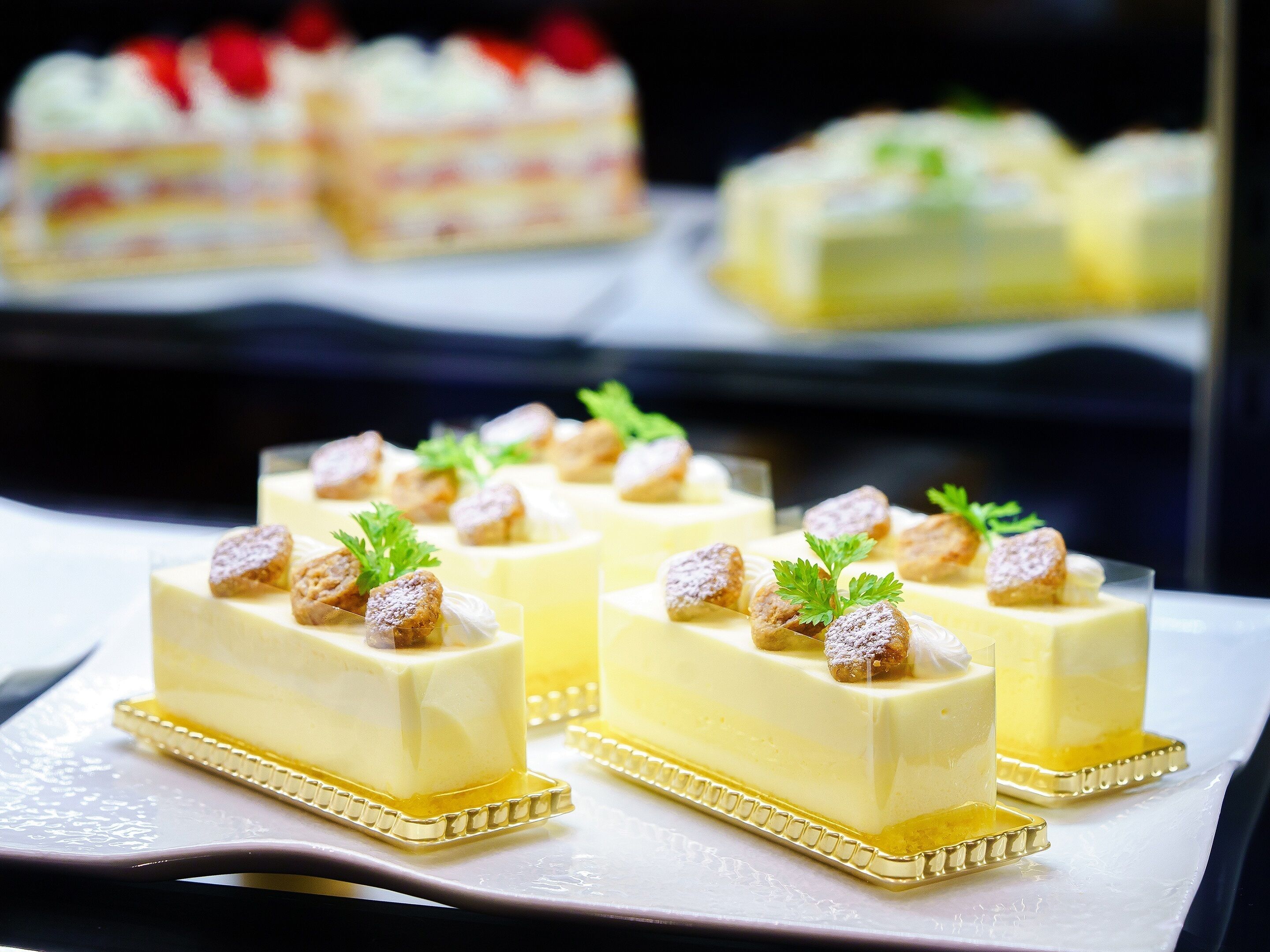Una presentación de postres con pasteles cuadrados cubiertos de nueces y perejil.