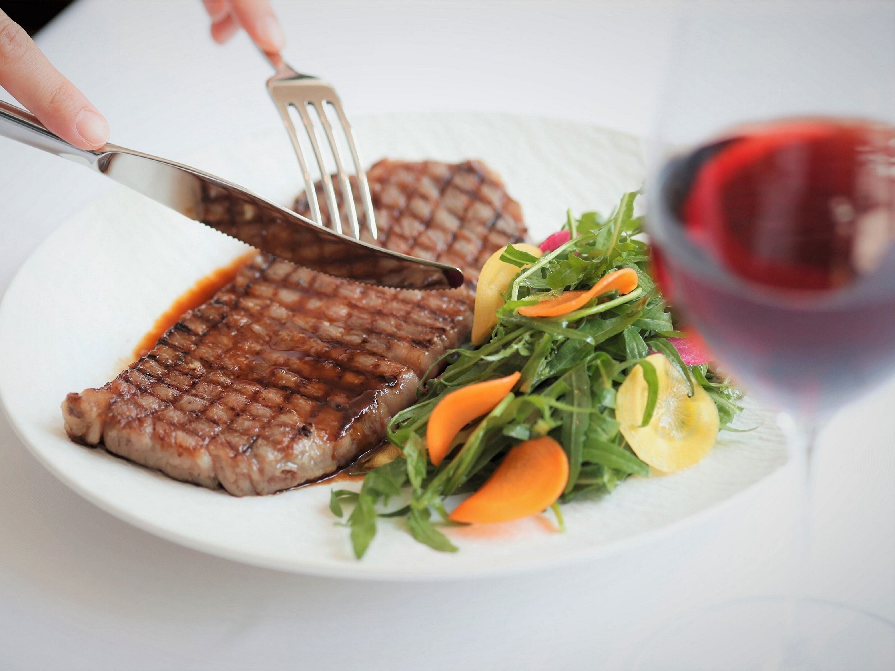 A plate with grilled steak, a salad, and a glass of red wine.