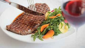 A plate with grilled steak, a salad, and a glass of red wine.