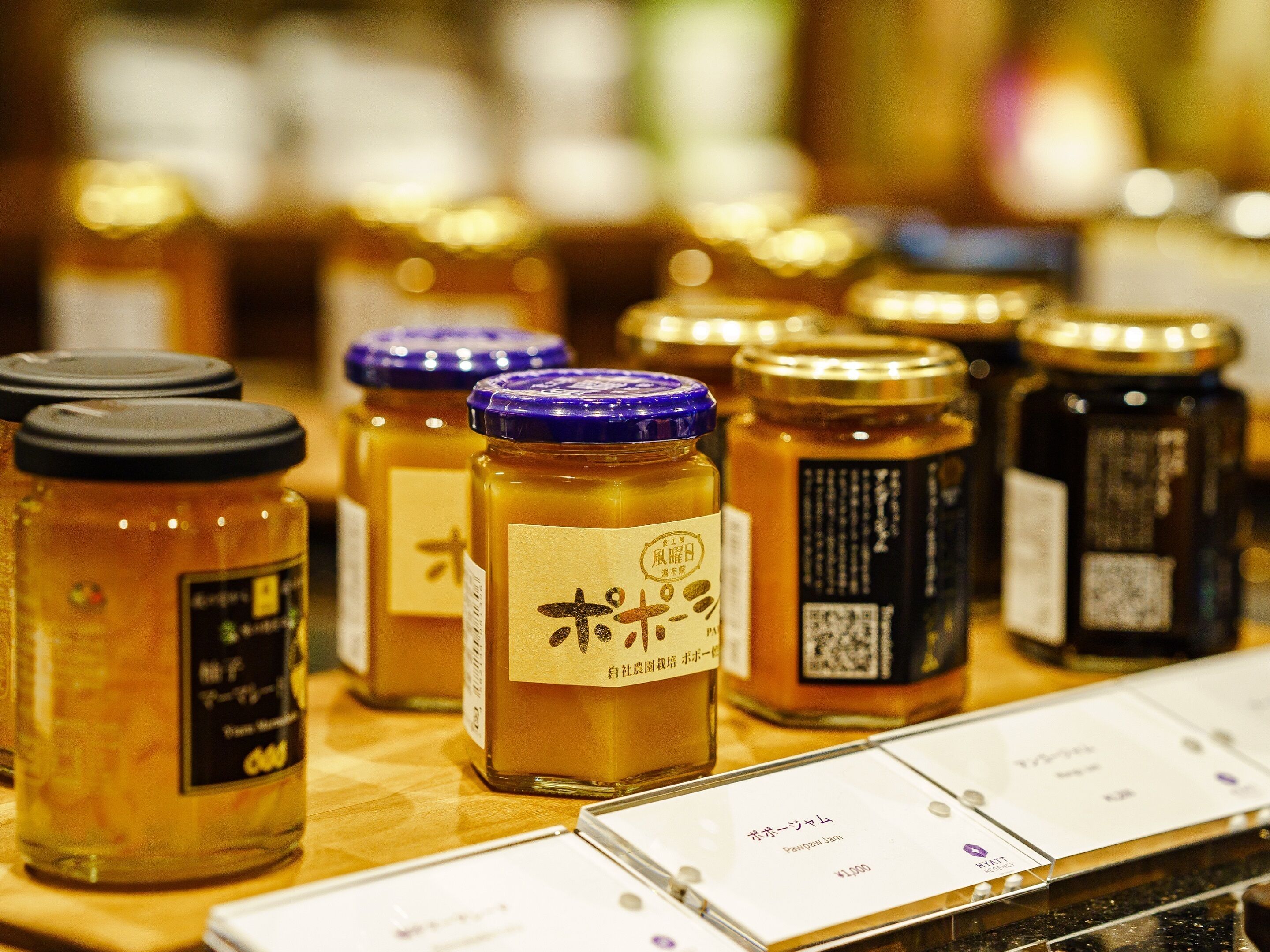 Une présentation de pots de miel, chacun portant une étiquette, disposés sur une surface en bois.