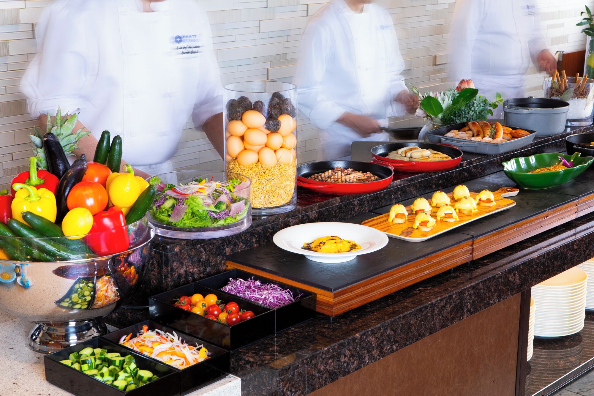 A buffet with various food items and a chef in the background.