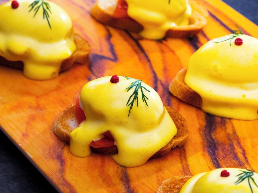 En träbricka med flera smörgåsar med ägg benedict.