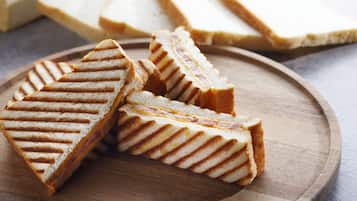 A wooden board with several triangular sandwiches.