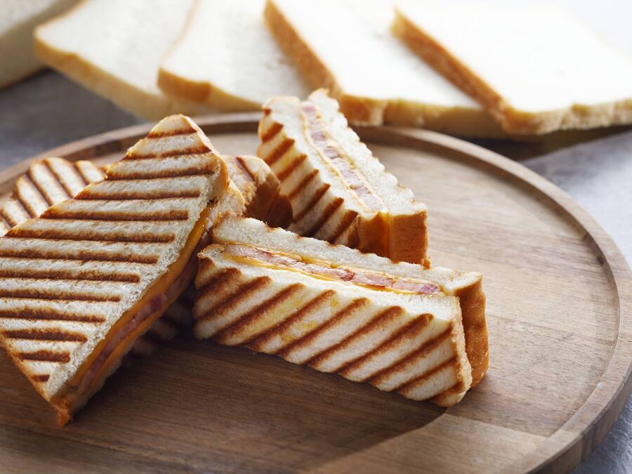 A wooden board with several triangular sandwiches.
