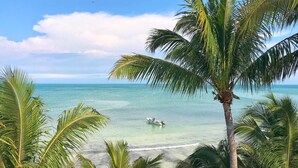 Uma praia com águas turquesa cristalinas, um barco e palmeiras.