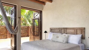 Quarto com cama grande, cabeceira de madeira e rede.