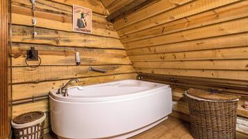 A wooden cabin interior with a white bathtub, a wicker basket, and a poster on the wall.