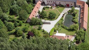 An aerial view of a building with a courtyard, a small pond, and surrounding greenery.