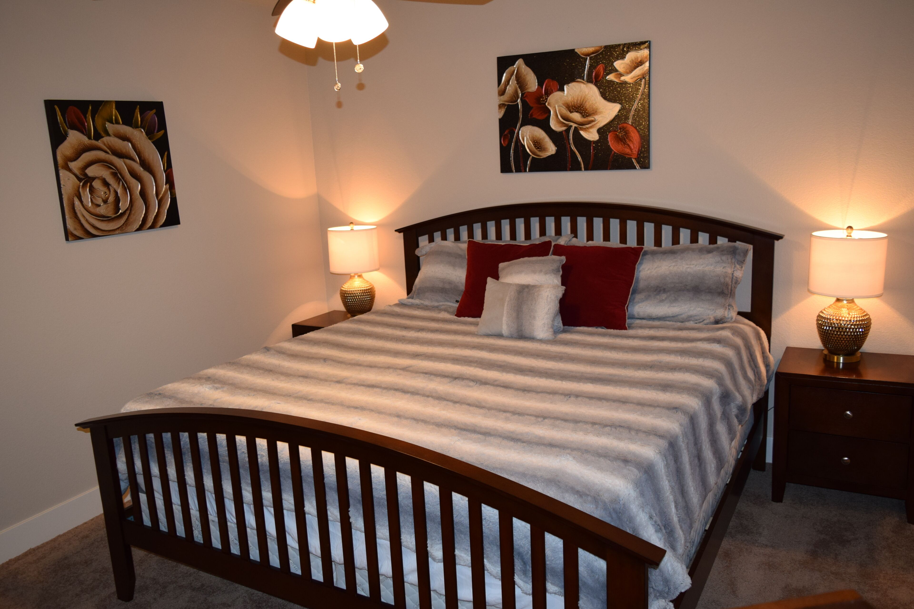 Un dormitorio con una cama de madera, dos mesitas de noche con lámparas y dos lámparas de pared.