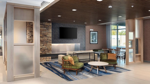 A modern lounge area with a stone accent wall, a flat-screen TV, comfortable seating, and a large window providing natural light.