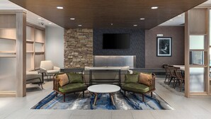 A modern lounge area with a stone accent wall, a flat-screen TV, and a seating arrangement.