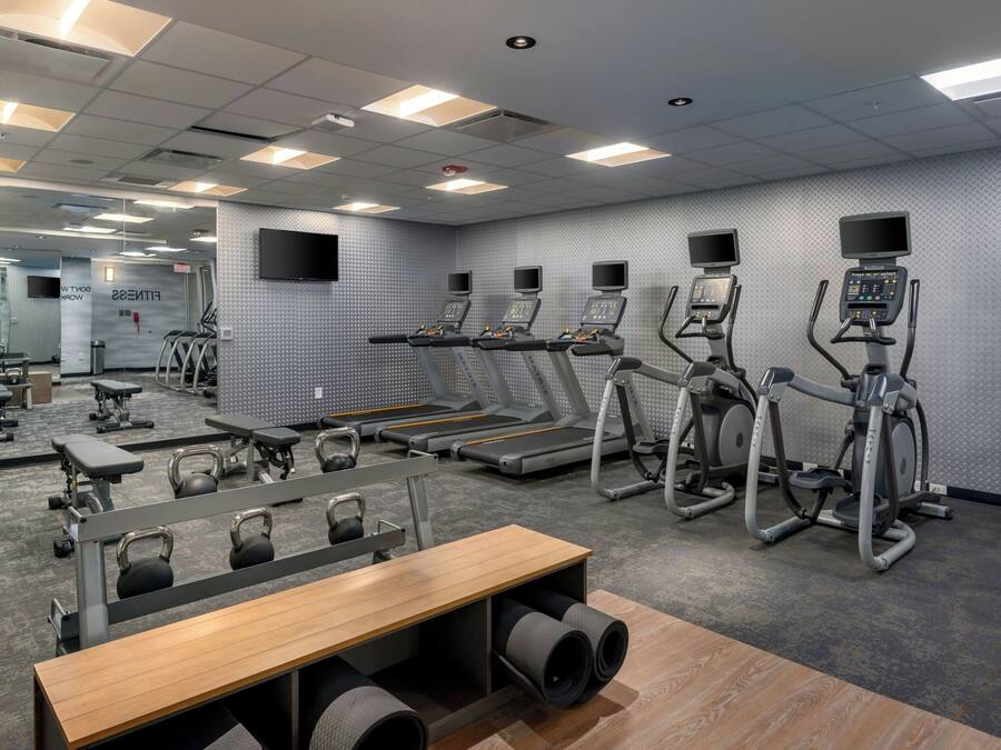 Ein Fitnessstudio mit Laufbändern, Crosstrainern und Gewichten.