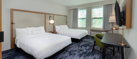 A hotel room with two beds, a desk, a chair, and a TV.