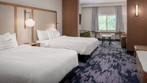 A hotel room with two beds, a desk, a chair, and a window with curtains.