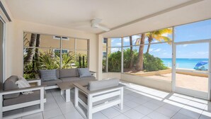 Um quarto amplo com uma grande janela que oferece vista para a praia e palmeiras.