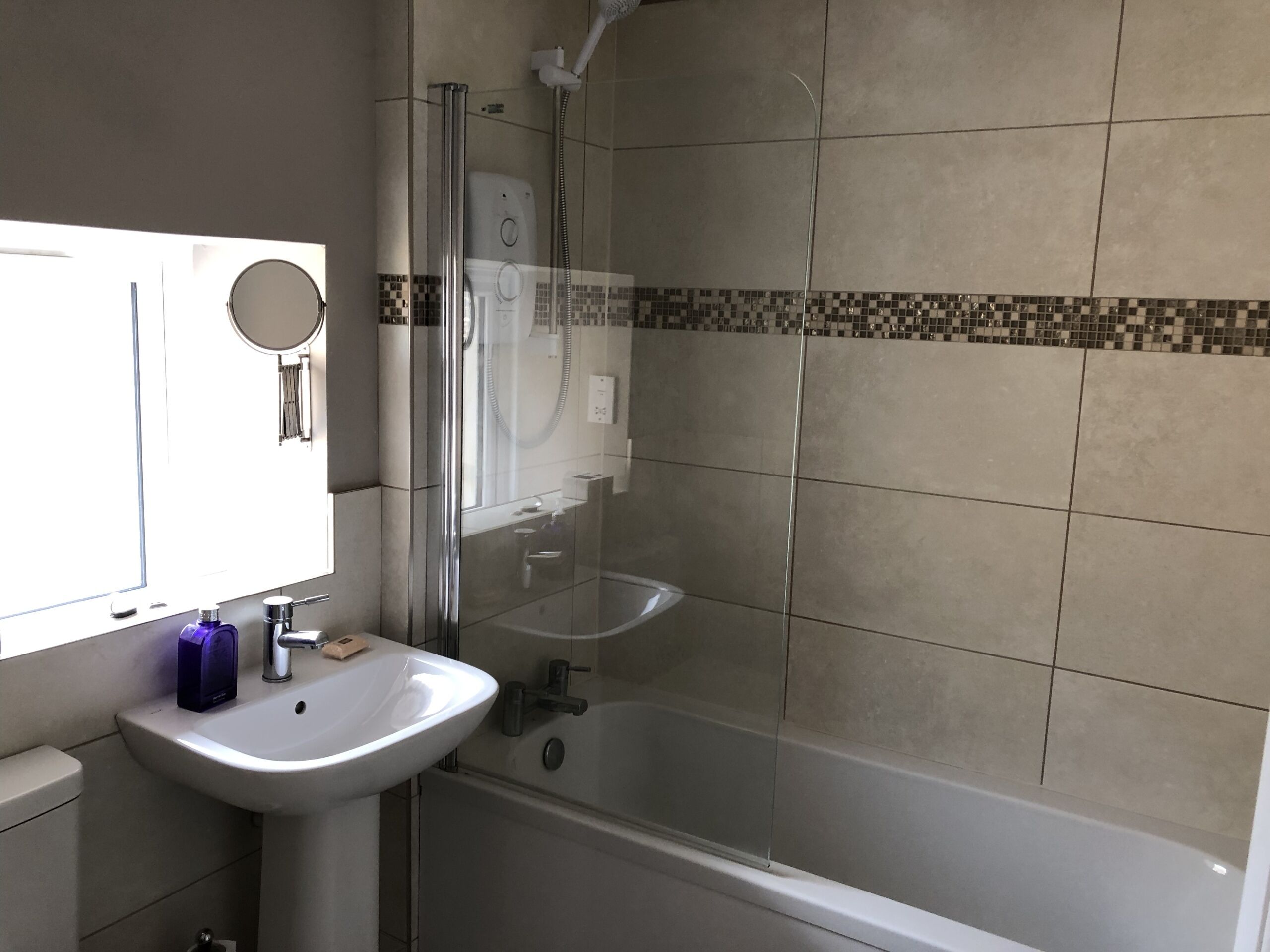 Une salle de bain avec une douche à parois de verre, un lavabo blanc et un miroir.
