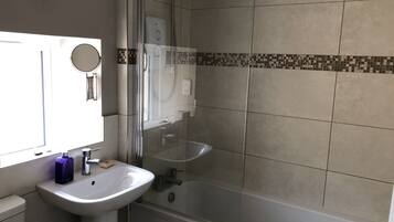 Une salle de bain avec une douche à parois de verre, un lavabo blanc et un miroir.