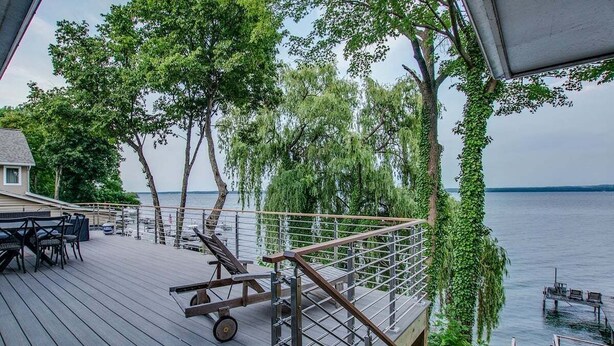 A wooden deck with outdoor furniture, a metal railing, and a view of the water.