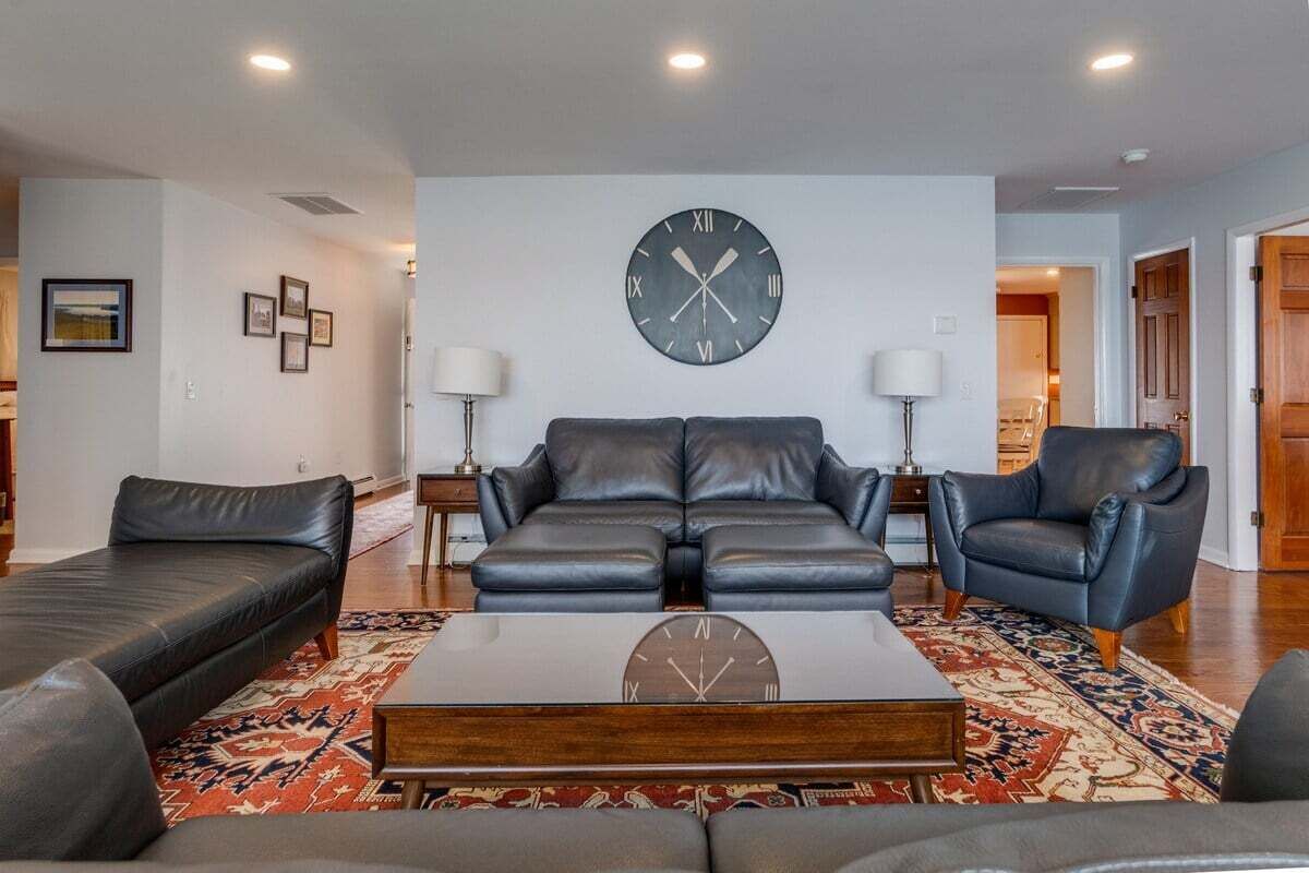 Una sala de estar moderna con un juego de sofá, una mesa de centro y un gran reloj de pared.