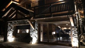 Eine Holzhütte mit Steinverkleidung, einem Balkon und einem Klavier im Inneren.