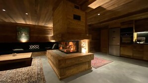 Ein gemütliches Blockhaus mit Kamin, Holzwänden, einer Sitzecke und einer Küchenzeile.