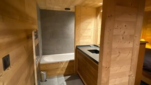 Eine gemütliche Holzjagdhütte mit einer kleinen Küchenzeile, einer Bank und einem Metallmülleimer.