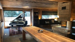 Ein modernes Interieur mit einem Flügel, einem langen Holztisch und einem Kamin.