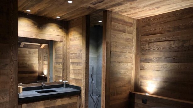 Ein modernes Badezimmer mit Holzvertäfelung, einem Waschbecken und einer Dusche.