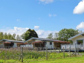 A row of single-story cabins with attached porches, surrounded by a grassy field and trees.