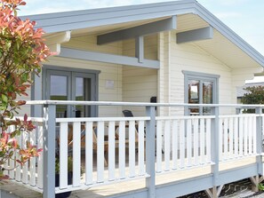 A building with a white exterior, a porch with white railings, and a door with glass panels.