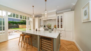 Una cocina amplia con una isla grande, taburetes de madera y un enfriador de vino.