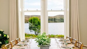 Un comedor con una mesa grande dispuesta para seis personas, con vista a un lago y colinas a lo lejos.