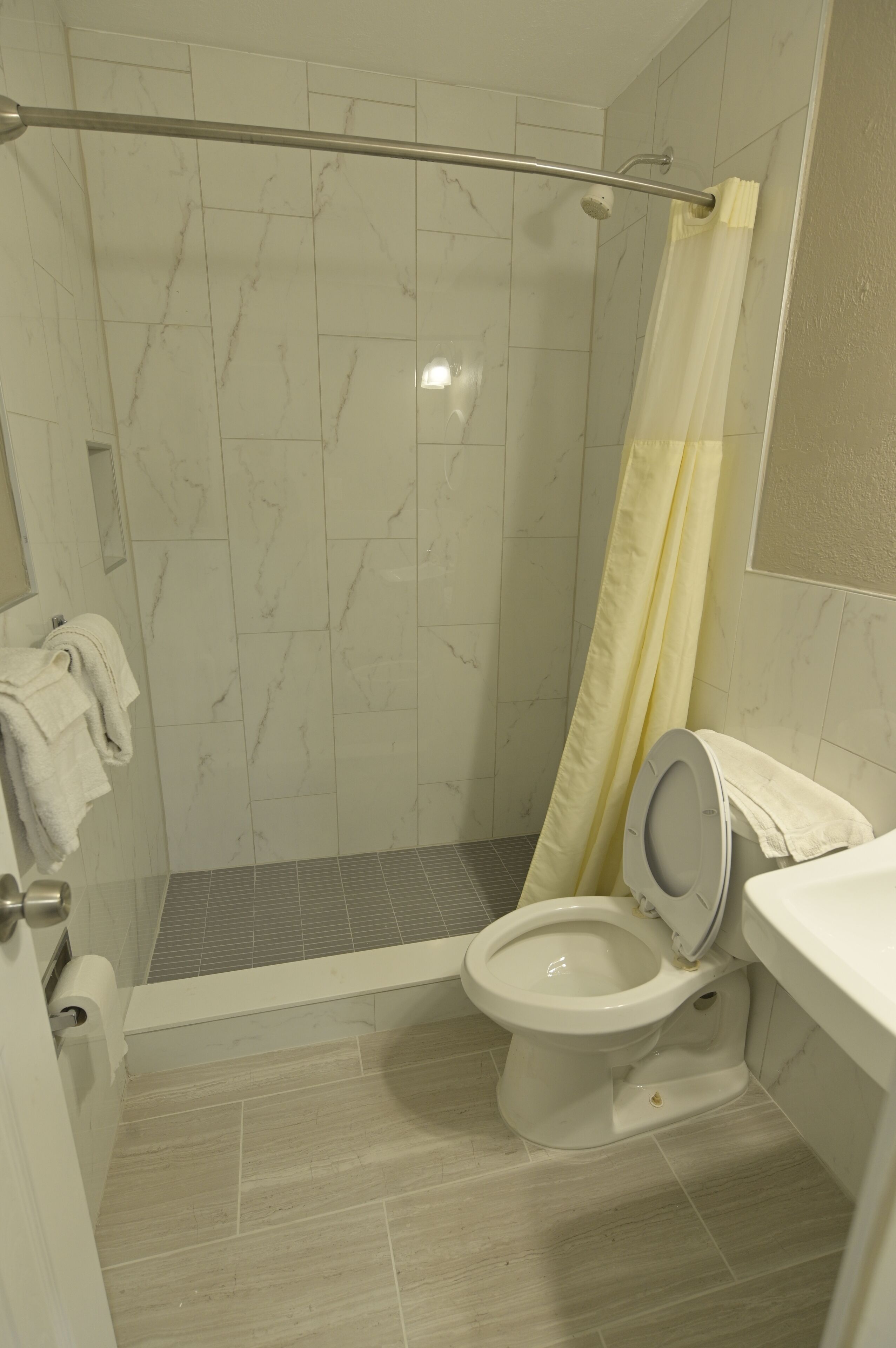 Een badkamer met een douche, toilet en een handdoekhouder.