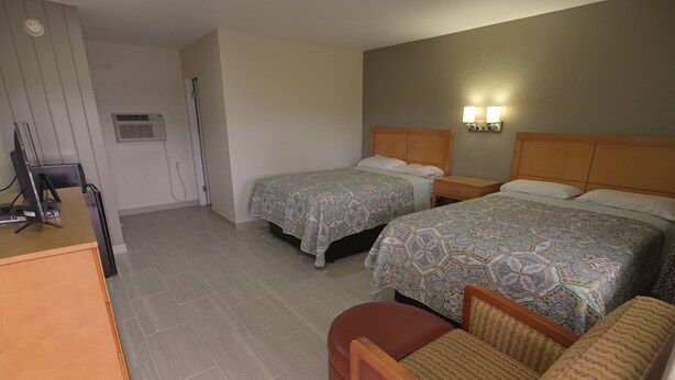 A hotel room with two beds, a desk, and a chair. - Deluxe Inn (Bunnell)