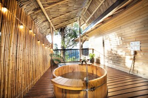A wooden spa area with a hot tub, bamboo walls, and a wooden deck.