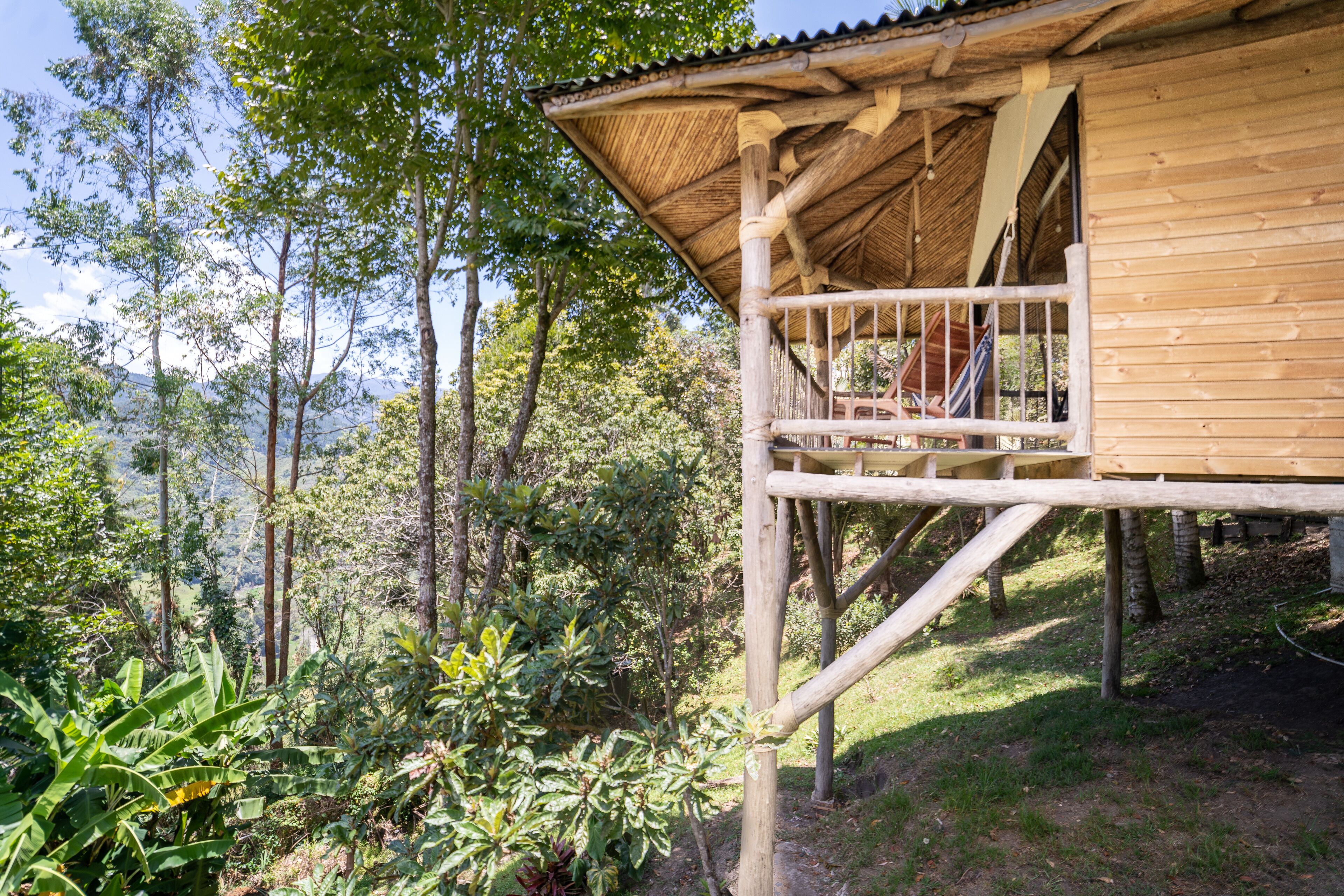A wooden cabin with a balcony overlooking a forested area.