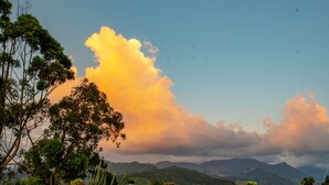 Terraza de madera con hidromasaje, rodeada de plantas en macetas y vistas a las montañas.