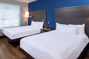 A hotel room with two single beds, a nightstand with a lamp, a telephone, and a window with blinds. - Tru By Hilton Elkhart (Elkhart)