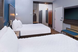 A hotel room with two beds, a TV, a wardrobe, and a mirror.