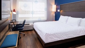 A hotel room with a bed, desk, chair, and a large window with blinds. - Tru By Hilton Elkhart (Elkhart)