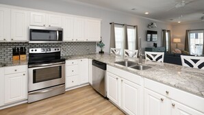 A modern kitchen with white cabinetry, stainless steel appliances, and a marble countertop. - 5 Bedroom Oceanview House with a Private Pool! Stingray (Surfside Beach)