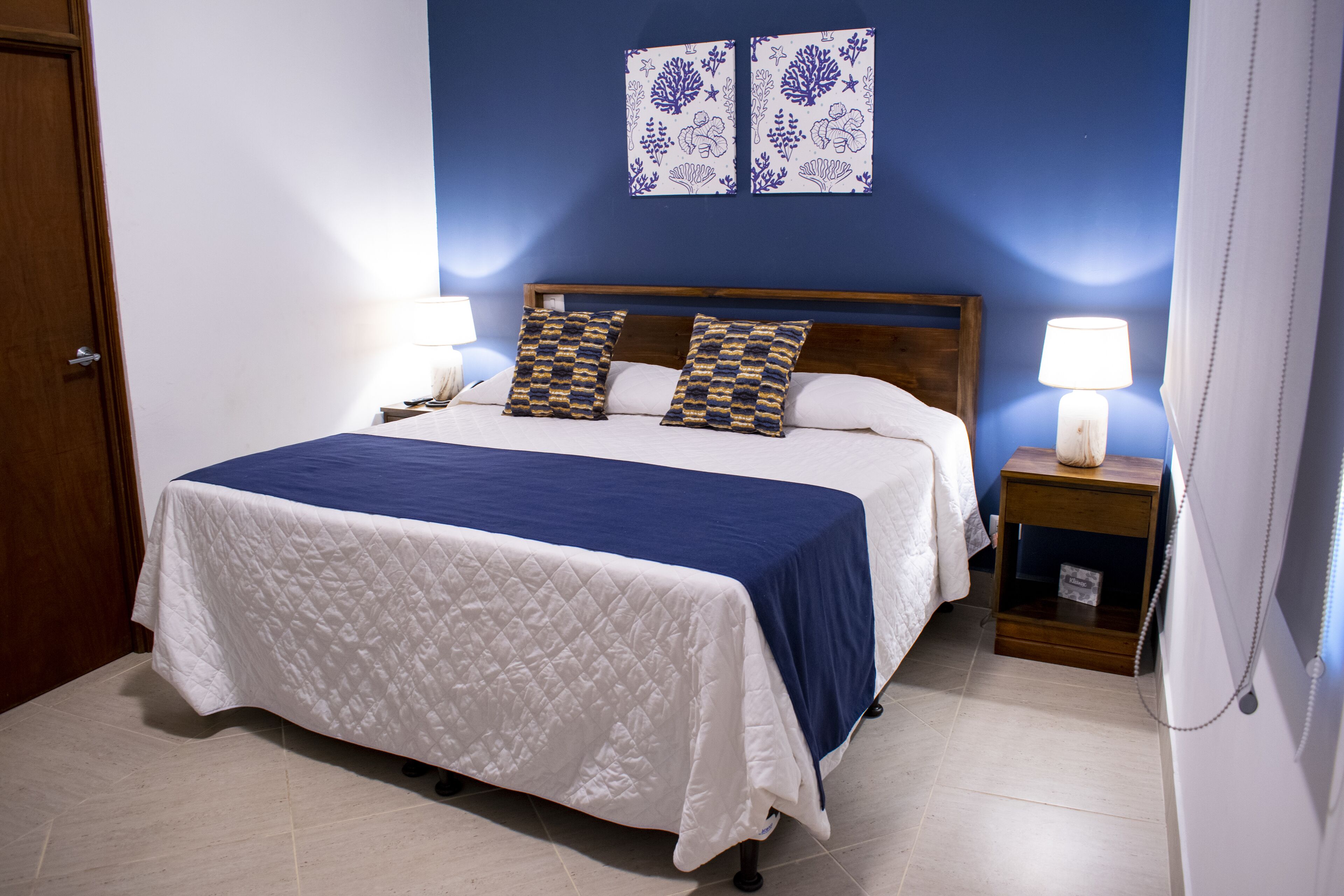 A bedroom with a bed, two bedside tables, a nightstand, and wall art.